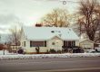 Charming snowy house with decorated porch, capturing winter tranquility.