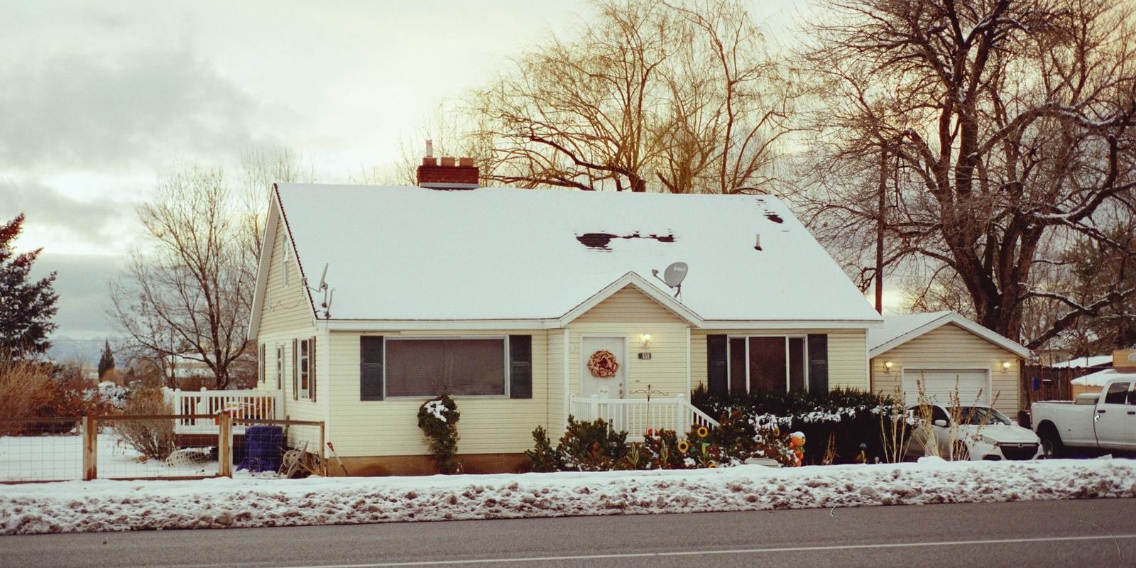 Charming snowy house with decorated porch, capturing winter tranquility.