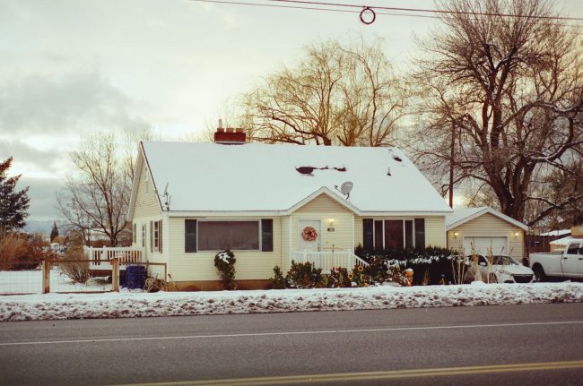 Charming snowy house with decorated porch, capturing winter tranquility.