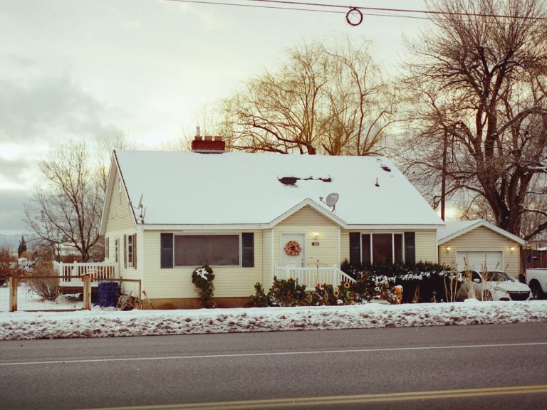 Charming snowy house with decorated porch, capturing winter tranquility.