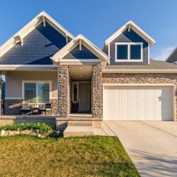A charming modern suburban home with a stone facade and a neatly maintained lawn.
