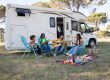 A family relaxing outdoors with a picnic and guitar by their camper, enjoying a sunny summer day in Portugal.