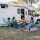 A family relaxing outdoors with a picnic and guitar by their camper, enjoying a sunny summer day in Portugal.