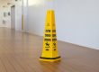 a yellow caution cone sitting on top of a hard wood floor