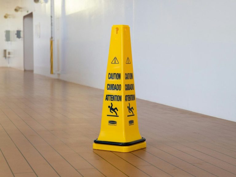 a yellow caution cone sitting on top of a hard wood floor