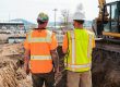 men in safety vests standing in front of a construction vehicle