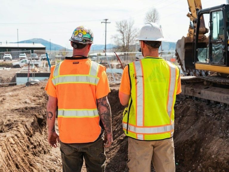 men in safety vests standing in front of a construction vehicle