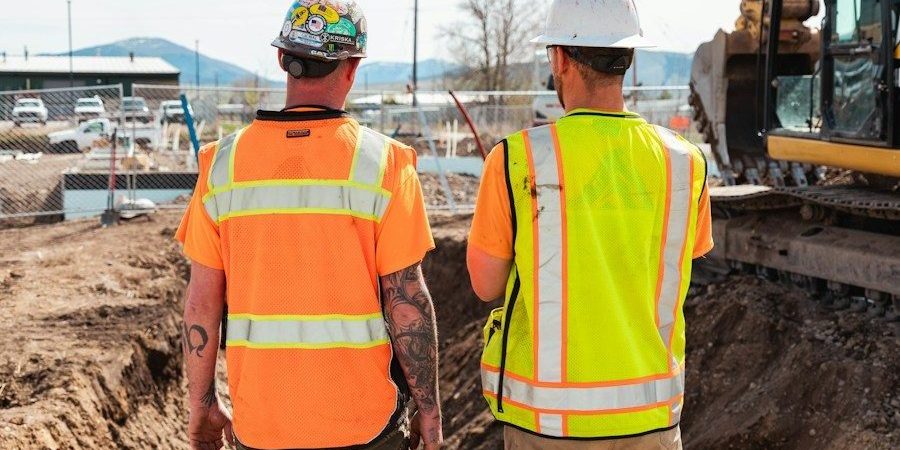 men in safety vests standing in front of a construction vehicle