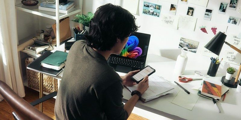 Man working at desk with laptop and phone