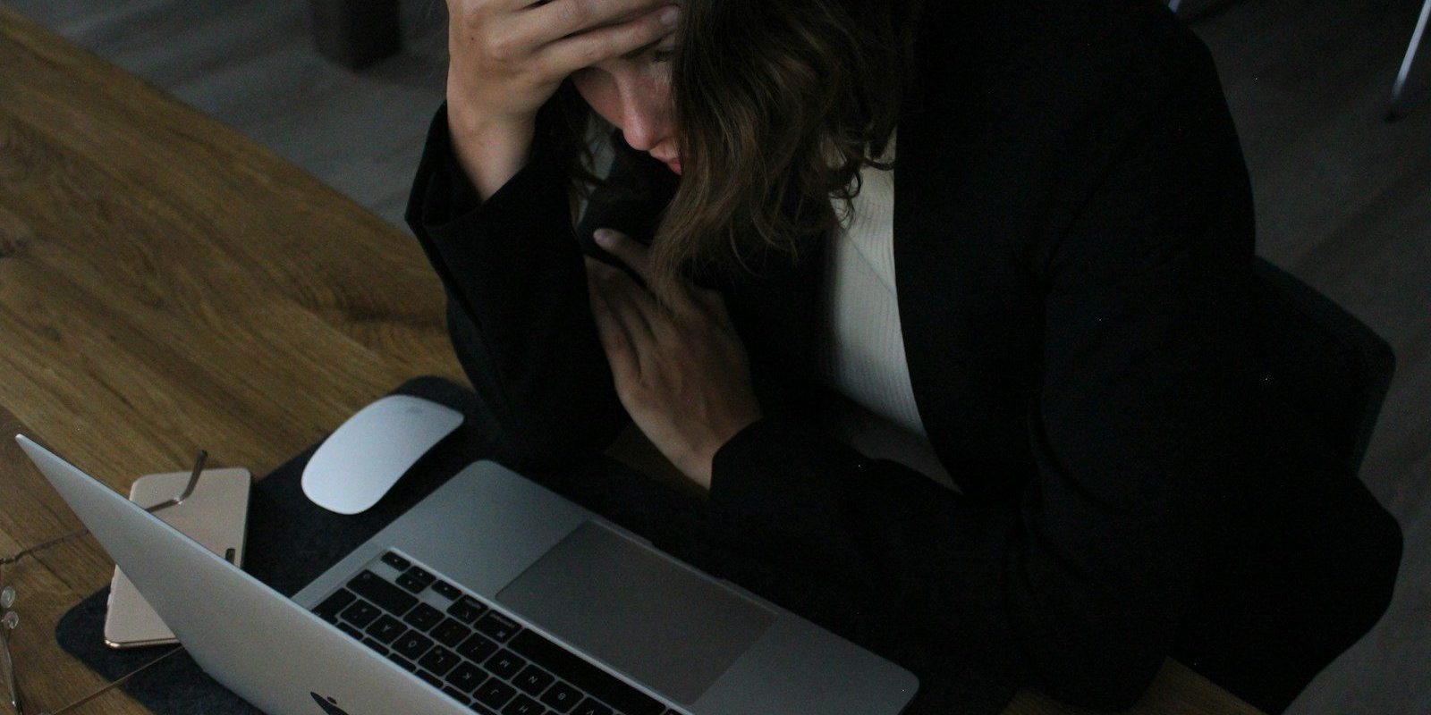 stressed woman with head in hands at laptop