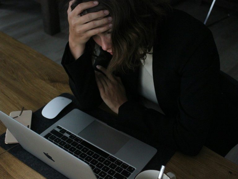 stressed woman with head in hands at laptop